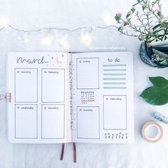 an open planner book sitting on top of a table next to some flowers and candles