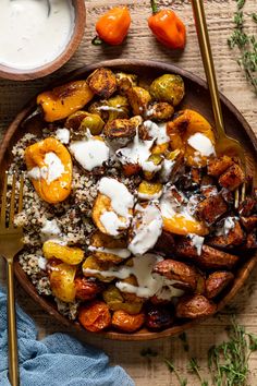 a wooden bowl filled with potatoes and other vegetables next to a cup of yogurt