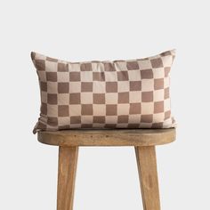 a brown and white checkered pillow sitting on top of a wooden stool