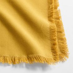 a yellow blanket with fringes laying on top of it