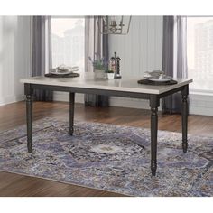 a dining room table with two place settings on top and an area rug in the middle