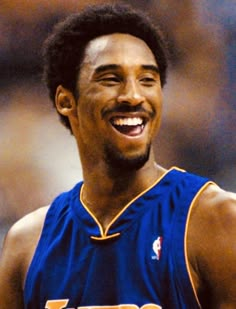 a close up of a person wearing a purple uniform and smiling at the camera while holding a basketball in his hand