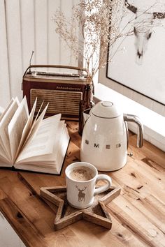 an open book and cup of coffee sit on a wooden table next to two books