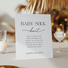 a baby sock sign sitting on top of a table next to a glass filled with water