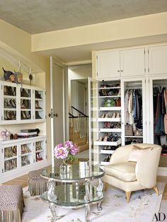 the closet is full of shoes and other things to wear in this room, as well as a glass table with flowers on it