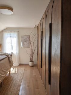 an empty bedroom with wood floors and large closets in the corner next to the bed