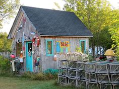 a small wooden building sitting in the middle of a field with lots of junk on it