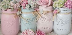 four painted mason jars with flowers in them