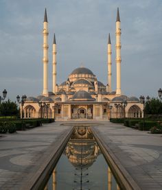 a large building with two tall towers next to a water fountain in front of it