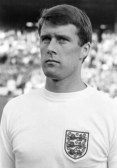 a man standing in front of a crowd wearing a white shirt with an england crest on it