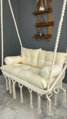 a white swing bed hanging from the ceiling in a room with gray walls and carpet