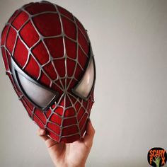 a hand holding up a red spider man mask