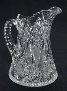 a glass pitcher sitting on top of a black table next to a knife and fork