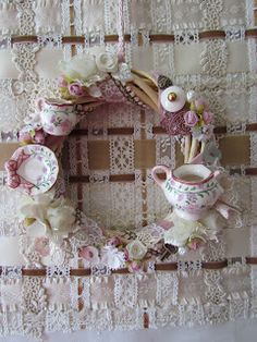 a wreath made out of tea cups and saucers on a lace doily background