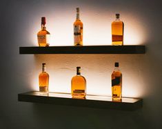 several bottles of whiskey are lined up on the shelf in front of a wall light