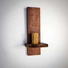 a piece of wood with a candle on it hanging from the wall next to a white wall