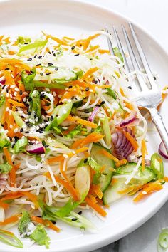 a salad with carrots, cucumbers and shredded cheese on a white plate