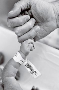 a black and white photo of a person holding a baby's hand