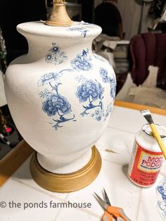 a blue and white vase sitting on top of a table next to some paintbrushes