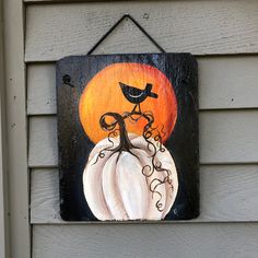 a sign on the side of a house with a bird sitting on top of a pumpkin