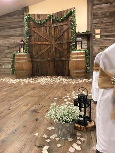 the ceremony room is decorated with white flowers and greenery, along with wooden barrels