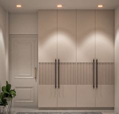 an empty room with white cupboards and plants on the floor in front of it