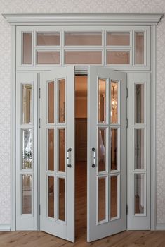 an open white double door in a room with wood floors and wall paper on the walls