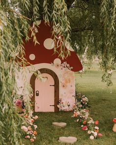 a mushroom shaped house with flowers around it and a door in the grass next to some rocks