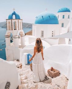 a woman in a white dress is standing on the edge of a building overlooking the water