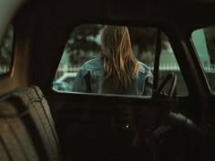 a woman sitting in the back seat of a car looking at her rear view mirror