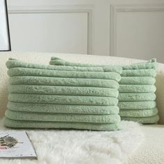 a stack of folded towels sitting on top of a white couch next to a book