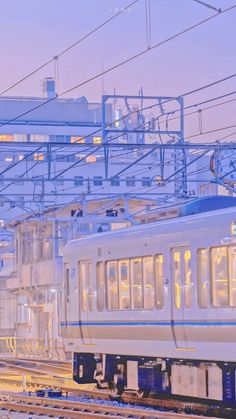 a white train traveling down train tracks next to a station with lots of power lines