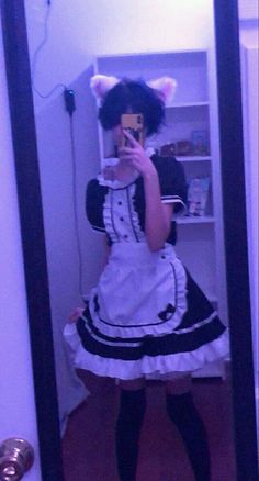 a woman taking a selfie in front of a mirror wearing a dress and cat ears