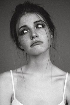 a black and white photo of a woman with freckles on her face looking at the camera