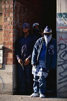 three men standing in an open doorway with graffiti on the walls