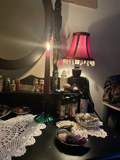 a table topped with lots of clutter next to a lamp