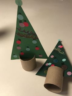 two christmas trees made out of toilet paper on top of a white table with confetti