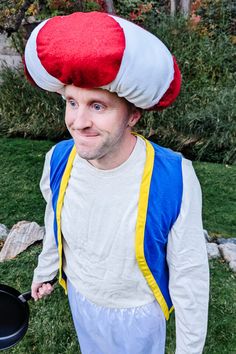 a man wearing a red, white and blue mushroom hat while holding a frying pan