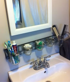 a bathroom sink with toothbrushes, combs and other items