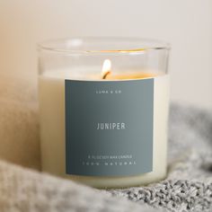 a white candle sitting on top of a blanket next to a gray and white label