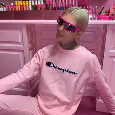 a woman with pink hair and sunglasses sitting in front of a counter