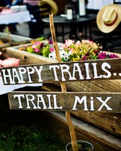 a sign that says happy trails trail mix in front of some flowers and other items