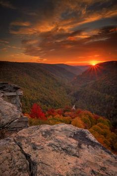 the sun is setting over a valley with mountains in the background and trees on both sides