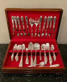 an assortment of silverware in a red case