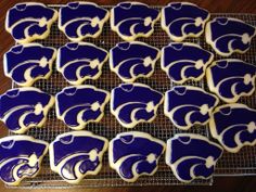 cookies decorated with royal blue and white frosting are on a cooling rack, ready to be eaten