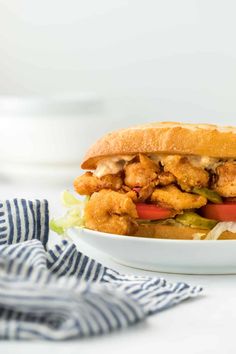 a chicken sandwich with lettuce and tomatoes in a white bowl