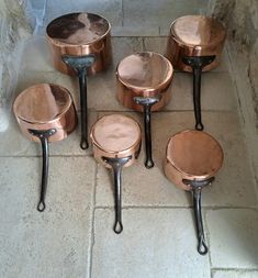 several copper colored pots and pans sitting on the floor