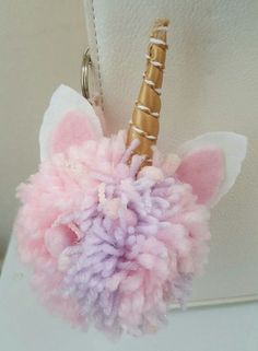 a pink and purple pom - pom keychain hanging from a hook