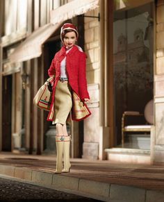 the doll is wearing a red jacket and beige skirt with gold trim around her neck