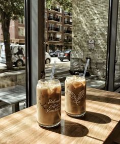 two iced coffees sitting on top of a wooden table